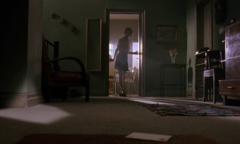 Movie still from “The Cement Garden” (1993), directed by Andrew Birkin – A woman standing in a doorway in a room; Wide shot, Low angle