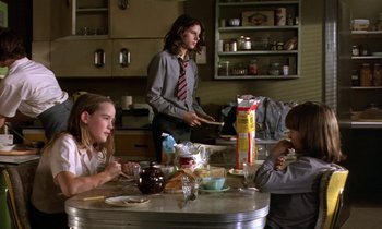 Movie still from “The Cement Garden” (1993), directed by Andrew Birkin – A group of people sitting at a table eating food; Medium shot, Low angle