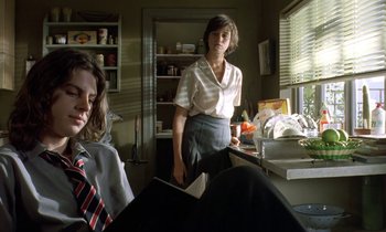Movie still from “The Cement Garden” (1993), directed by Andrew Birkin – A woman standing in front of a kitchen counter; Medium shot, Low angle