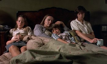 Movie still from “The Cement Garden” (1993), directed by Andrew Birkin – A group of people laying in a bed together; Medium shot, High angle