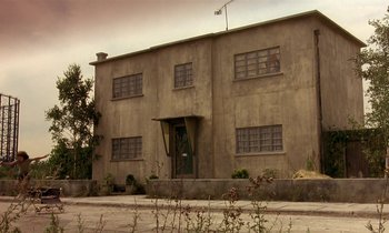 Movie still from “The Cement Garden” (1993), directed by Andrew Birkin – An old building with many windows on the side of the building; Extreme Wide shot, Low angle