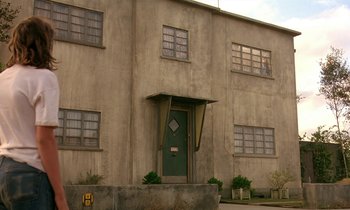 Movie still from “The Cement Garden” (1993), directed by Andrew Birkin – A building with a green door and a window; Extreme Wide shot, Low angle