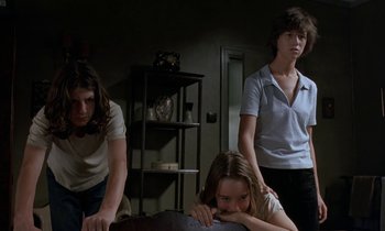 Movie still from “The Cement Garden” (1993), directed by Andrew Birkin – A group of young people standing around a table; Medium shot, Low angle