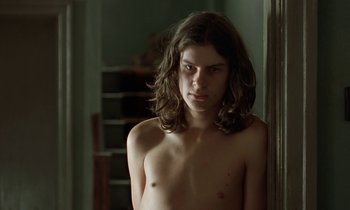 Movie still from “The Cement Garden” (1993), directed by Andrew Birkin – A man with long hair is standing in front of a mirror; Close Up shot, Low angle