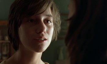 Movie still from “The Cement Garden” (1993), directed by Andrew Birkin – A young woman looking at the camera with a smile; Close Up shot, Over the shoulder angle