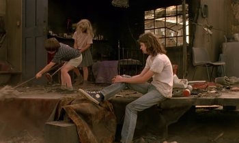 Movie still from “The Cement Garden” (1993), directed by Andrew Birkin – A group of young people sitting on top of rocks; Wide shot, High angle