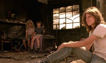 Movie still from “The Cement Garden” (1993), directed by Andrew Birkin – Two women sitting in a room with a man sitting on the floor; Wide shot, Low angle