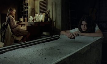 Movie still from “The Cement Garden” (1993), directed by Andrew Birkin – A man is leaning over a table in a room; Medium shot, High angle