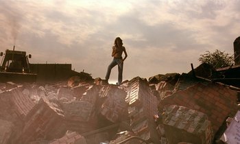 Movie still from “The Cement Garden” (1993), directed by Andrew Birkin – A woman standing on top of a pile of rubble; Wide shot, Low angle