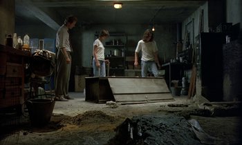Movie still from “The Cement Garden” (1993), directed by Andrew Birkin – Three people in a room working on a project; Wide shot, High angle