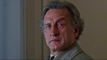 Movie still from “The Changeling” (1980), directed by Peter Medak – An older man with gray hair and a gray jacket; Close Up shot, Low angle