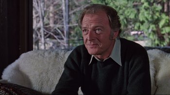 Movie still from “The Changeling” (1980), directed by Peter Medak – An older man sitting on top of a white couch; Close Up shot, Over the shoulder angle