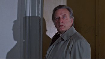 Movie still from “The Changeling” (1980), directed by Peter Medak – An older man wearing a trench coat and a tie; Close Up shot, Low angle