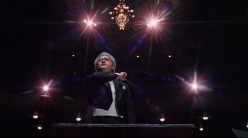 Movie still from “The Changeling” (1980), directed by Peter Medak – A man in a suit and tie holding a cane in his hand; Medium shot, Low angle