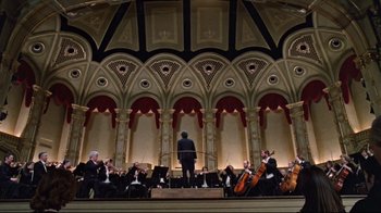 A conductor stands in front of a orchestra