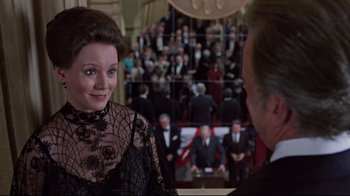 Movie still from “The Changeling” (1980), directed by Peter Medak – A woman in a black dress talking to a man in a black suit; Medium shot, Over the shoulder angle