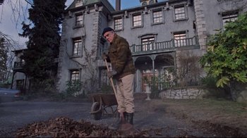 Movie still from “The Changeling” (1980), directed by Peter Medak – An old man is standing in front of an old house; Wide shot, Low angle