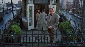 Movie still from “The Changeling” (1980), directed by Peter Medak – A man standing on a porch with two other men; Wide shot, High angle