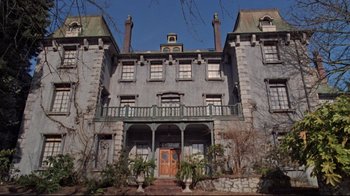 Movie still from “The Changeling” (1980), directed by Peter Medak – A very large gray building with a large balcony; Extreme Wide shot, Low angle