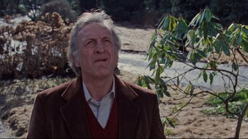 Movie still from “The Changeling” (1980), directed by Peter Medak – An older man standing in front of some trees; Close Up shot, Low angle