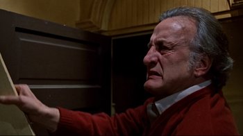 Movie still from “The Changeling” (1980), directed by Peter Medak – An older man in a red sweater pointing to a door; Close Up shot, Low angle