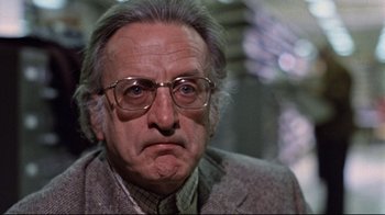Movie still from “The Changeling” (1980), directed by Peter Medak – An older man wearing glasses and a jacket; Close Up shot, Low angle