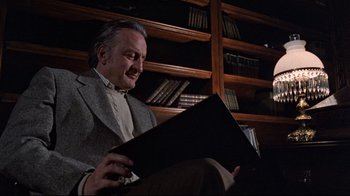 Movie still from “The Changeling” (1980), directed by Peter Medak – An older man sitting in front of a book case; Medium shot, Low angle