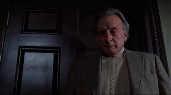 Movie still from “The Changeling” (1980), directed by Peter Medak – An older man wearing a jacket and a sweater; Close Up shot, Low angle