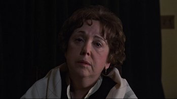 Movie still from “The Changeling” (1980), directed by Peter Medak – An older woman sitting in front of a black background; Close Up shot, High angle