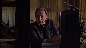 Movie still from “The Changeling” (1980), directed by Peter Medak – An older man sitting at a computer in a dark room; Medium shot, Low angle