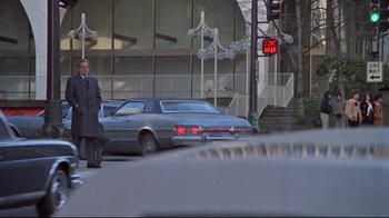 Movie still from “The Changeling” (1980), directed by Peter Medak – A man in a suit and tie standing next to a car; Wide shot, Low angle