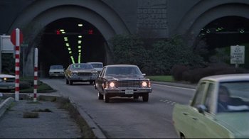 Movie still from “The Changeling” (1980), directed by Peter Medak – A group of cars driving down a street; Extreme Wide shot, Low angle