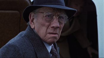 Movie still from “The Changeling” (1980), directed by Peter Medak – An old man wearing a hat and glasses; Close Up shot, Low angle
