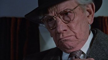 Movie still from “The Changeling” (1980), directed by Peter Medak – An older man wearing glasses and a hat; Close Up shot, Low angle
