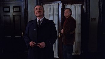 Movie still from “The Changeling” (1980), directed by Peter Medak – Two men standing next to each other in front of a door; Medium shot, Low angle