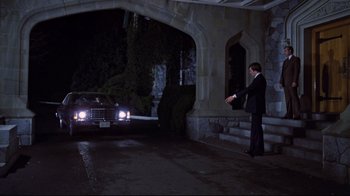 Movie still from “The Changeling” (1980), directed by Peter Medak – A man standing in front of a car at night; Wide shot, High angle