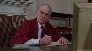Movie still from “The Changeling” (1980), directed by Peter Medak – An older man sitting at a table writing on a piece of paper; Close Up shot, Low angle