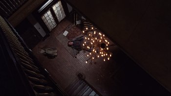 Movie still from “The Changeling” (1980), directed by Peter Medak – A man laying on the floor of a house; Wide shot, Overhead angle