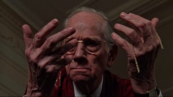 Movie still from “The Changeling” (1980), directed by Peter Medak – An old man wearing glasses and a red jacket; Close Up shot, Low angle