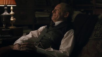 Movie still from “The Childhood of a Leader” (2015), directed by Brady Corbet – An older man sitting in a chair with his eyes closed; Medium shot, High angle