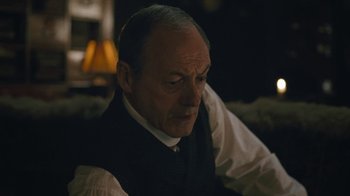Movie still from “The Childhood of a Leader” (2015), directed by Brady Corbet – An older man sitting in front of a lamp; Close Up shot, Low angle