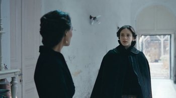 Movie still from “The Childhood of a Leader” (2015), directed by Brady Corbet – A woman standing in front of a mirror looking at herself in the mirror; Medium shot, Over the shoulder angle