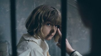Movie still from “The Childhood of a Leader” (2015), directed by Brady Corbet – A person touching a girl's face with a hand; Close Up shot, Over the shoulder angle