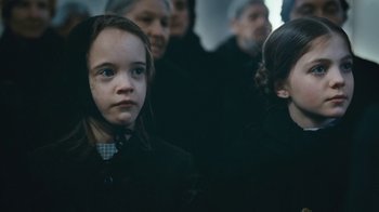 Movie still from “The Childhood of a Leader” (2015), directed by Brady Corbet – A little girl is standing next to another girl; Close Up shot, Over the shoulder angle
