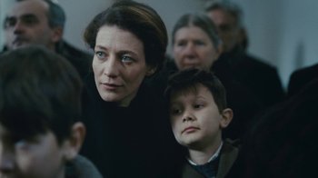 Movie still from “The Childhood of a Leader” (2015), directed by Brady Corbet – A woman and a boy in a crowd of people; Close Up shot, Over the shoulder angle