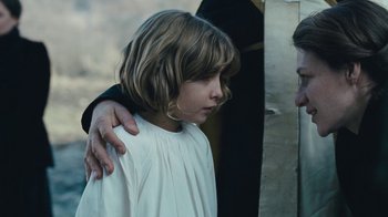 Movie still from “The Childhood of a Leader” (2015), directed by Brady Corbet – A young girl is being hugged by an older man; Close Up shot, Over the shoulder angle