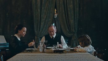 Movie still from “The Childhood of a Leader” (2015), directed by Brady Corbet – A group of people sitting at a dinner table; Medium shot, Over the shoulder angle