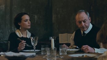 Movie still from “The Childhood of a Leader” (2015), directed by Brady Corbet – A man and a woman sitting at a dinner table; Medium shot, Over the shoulder angle
