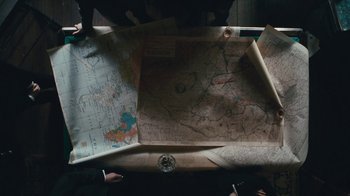 Movie still from “The Childhood of a Leader” (2015), directed by Brady Corbet – A map is laying on a table with a compass; Medium shot, Overhead angle
