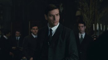 Movie still from “The Childhood of a Leader” (2015), directed by Brady Corbet – A man in a suit and tie standing in front of two other men; Medium shot, Low angle